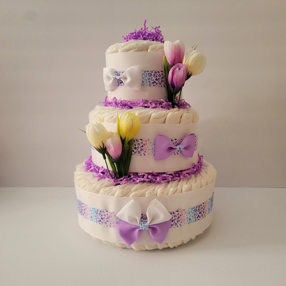 Handmade three-tier diaper cake with lavender ribbon, bows and tulips