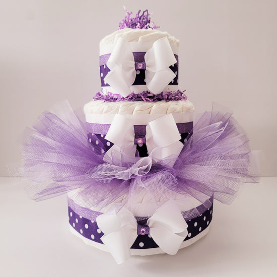 Elegant Tutu diaper cake with three tiers, purple polka dot ribbons, white bows with gemstones and a lavender wearable tutu