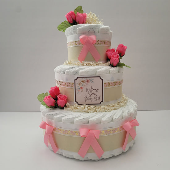 Floral diaper cake with three tiers, burlap and pink ribbons, pink bows, pink roses and a framed welcome baby sign
