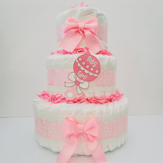 Elegant Pink diaper cake for a baby girl with three tiers, pink satin bows, lace ribbon and a pink baby rattle cutout